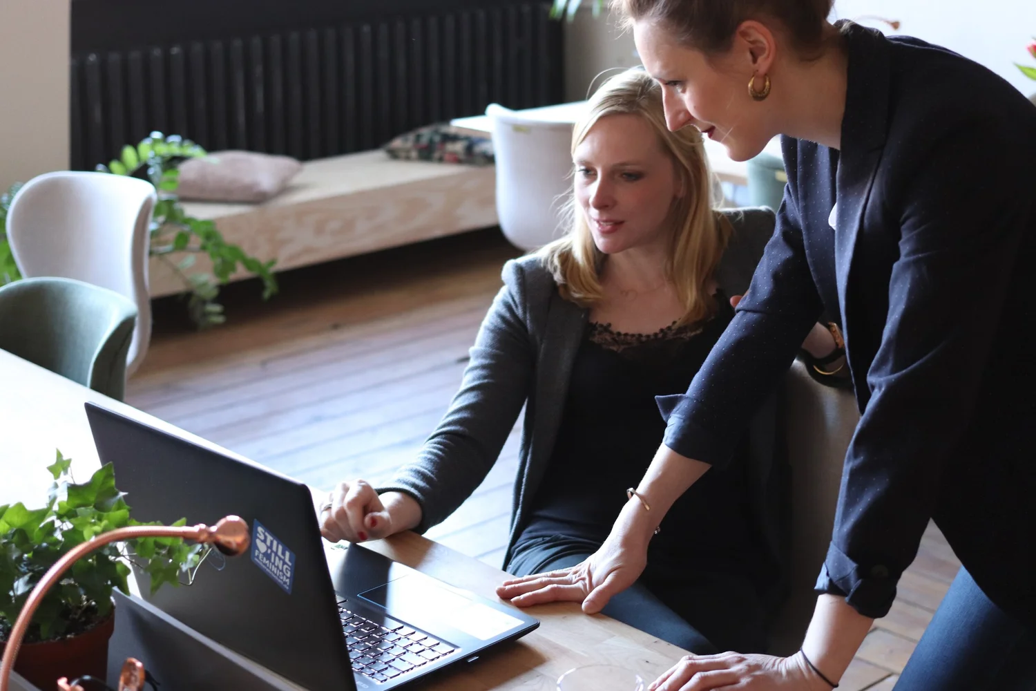 Two colleagues reviewing work on a laptop
